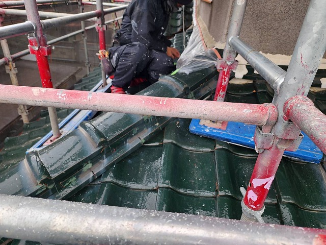 飯田市：瓦屋根の上で養生を行う塗装工