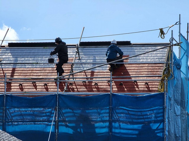 屋根足場の上で塗装を行う作業員