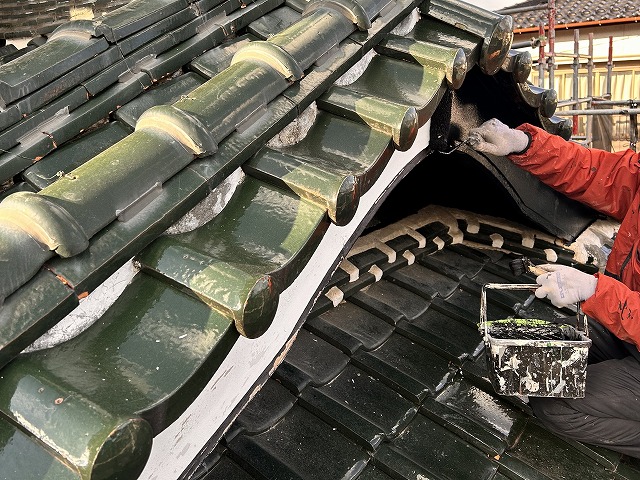 飯田市：瓦屋根の上で破風板への塗装を行っている塗装工
