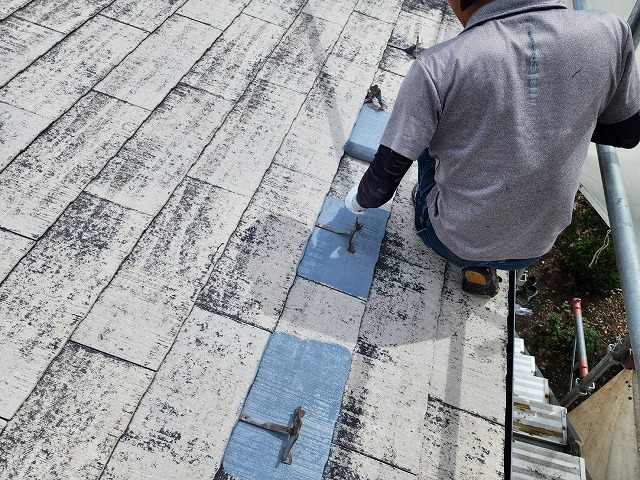 上伊那郡箕輪町：屋根塗装工事で雪止め金具の周辺に下塗りをする塗装工