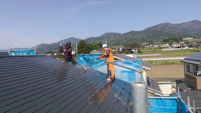屋根を高圧洗浄中の作業員