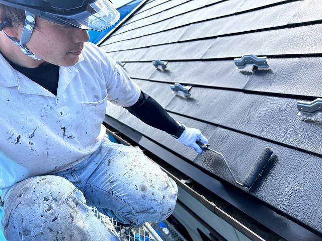 伊那市：木目柄の金属屋根にローラーで塗装を行う塗装工