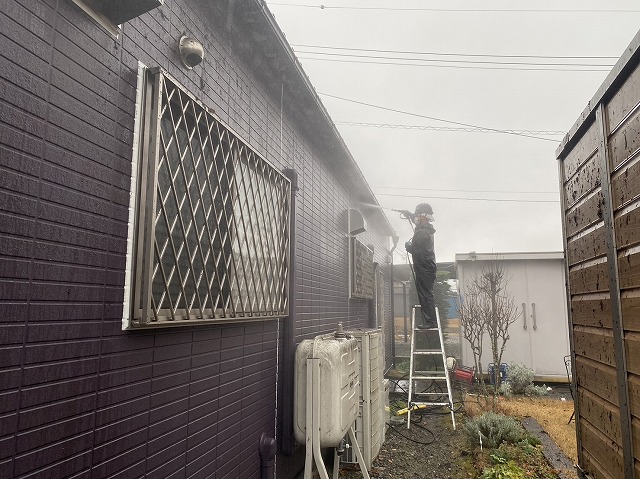 上伊那郡南箕輪村:店舗建物の外壁塗装工事の高圧洗浄を脚立で行っている様子