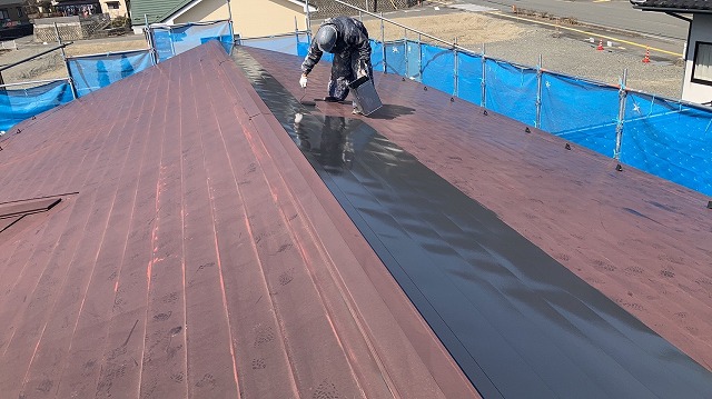 飯田市：色あせた金属屋根に1回目の塗装をする塗装工