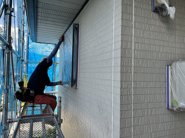 上伊那郡箕輪町：外壁塗装工事で窓に養生をする塗装職人