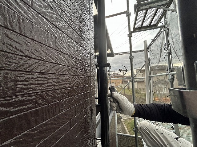 飯田市：竪樋へローラー塗装を行う塗装工
